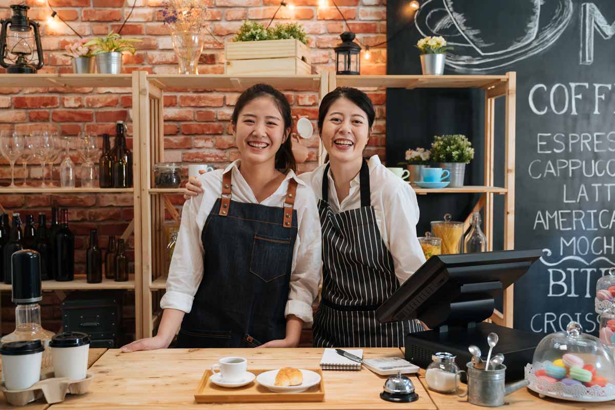 Two smiling small business owners stand behind the counter of their café, supported by Gesa Credit Union’s business banking services.